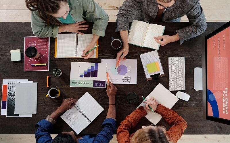 Marketing team discussing SEO strategy with analytics charts, laptops, and planning documents during a collaborative meeting.